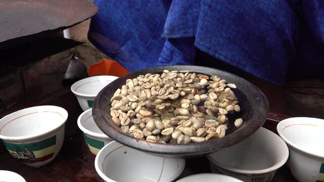 Hands of woman washing fresh coffee beans during traditional ceremony in tribal village in Ethiopia Africa
