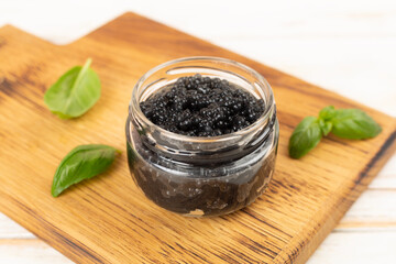Jar with black caviar on on wooden table