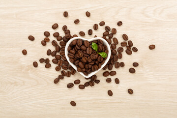 Roasted coffee beans with leaves on wooden background,top view