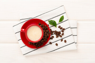 Cup of coffee with coffee beans and leaves on wooden background,top view