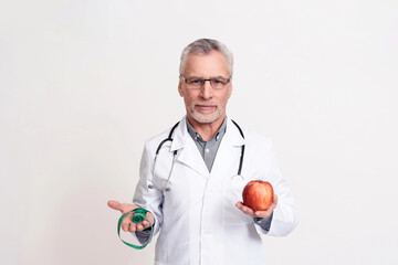 Portrait of doctor with stethoscope holding apple isolated.