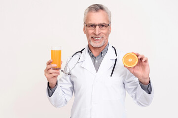 Portrait of doctor with stethoscope holding glass of juice and orange isolated.