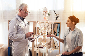 Doctor with stethoscope and female patient in office. Woman is telling symptoms.