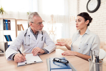 Doctor with stethoscope and female patient in office. Doctor is using tablet.