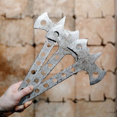 three metal axes in man hand, wooden block stand as target in background, throwing axes and knives,...