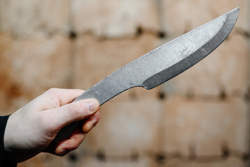 metal knife in man hand, wooden block stand as target in background, throwing knives, sports...
