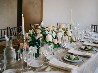 Elegant dining setup with floral arrangement and candles for a special event at an indoor venue