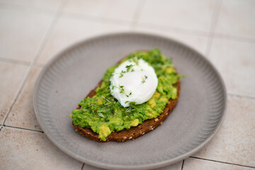 Smashed avocado sandwich with boiled poached egg with flowing yolk.