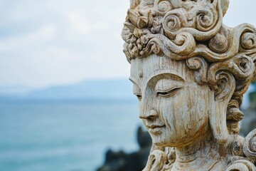 Obraz premium Weathered wooden statue of a serene figure, possibly a deity, overlooks the ocean.