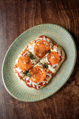 Delicious homemade pizza topped with fresh tomatoes and herbs on a textured plate, showcasing a golden crust and melted cheese. Perfect for food lovers.