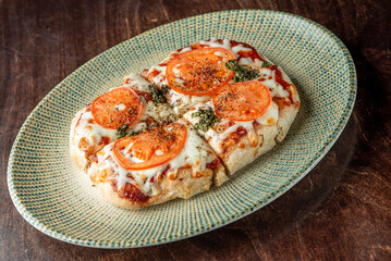 Delicious homemade pizza topped with fresh tomatoes and herbs on a textured plate, showcasing a...