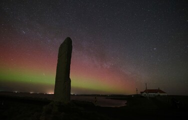 Northern lights and the milkyway over the watchstone in neolithic orkney in landscape