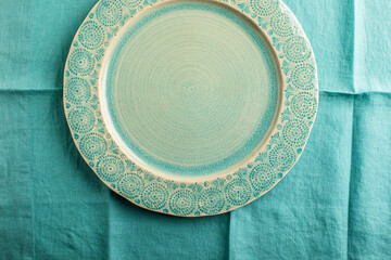 Empty green plate on folded aqua linen overhead
