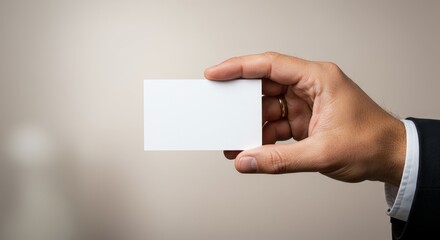 Fototapeta premium Hand Holding Blank Business Card - A hand extends, offering a blank white business card against a neutral background. It symbolizes opportunity, networking, connection, professionalism, and potential