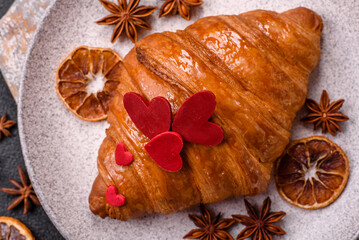 Sweet crispy croissant decorated with red hearts