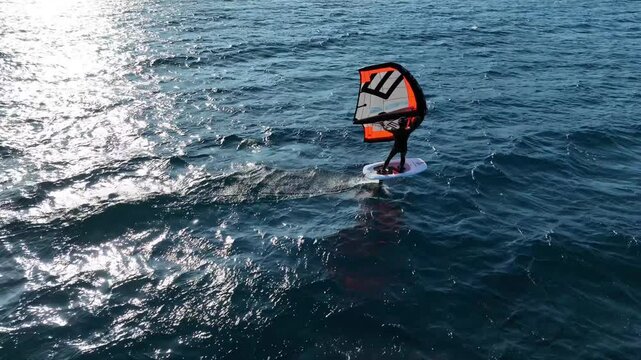 Aerial drone cinematic video of fit athlete practise hydro foil wing surfing in tropical exotic bay with emerald sea