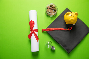 Graduation hat and diploma on the green background.