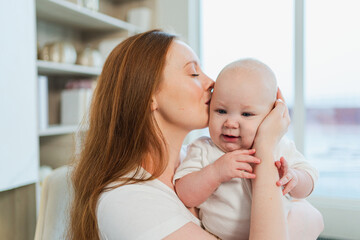 Happy family at home. Mother holding little toddler child daughter. Mom and baby girl relax playing having fun together at home. Mother hugs baby with love care. Mom of breast feeding baby