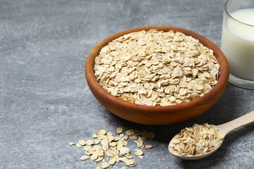 Composition with oatmeal flakes on gray background. Cooking breakfast