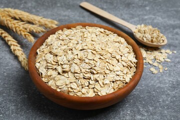 Composition with oatmeal flakes on gray background. Cooking breakfast