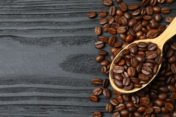 Fresh coffee beans in a spoon on wooden background