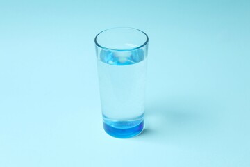 Transparent glass with water on blue background. Drinking clear water in the morning for health
