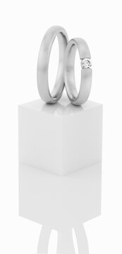 Wedding rings on top of white pedestal.