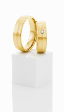 Wedding rings on top of white pedestal.