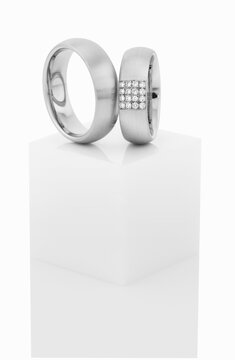 Wedding rings on top of white pedestal.