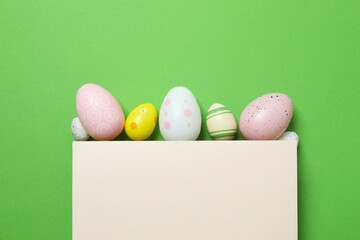 Happy Easter. Colorful eggs with paper card on green background, space for text or advertising