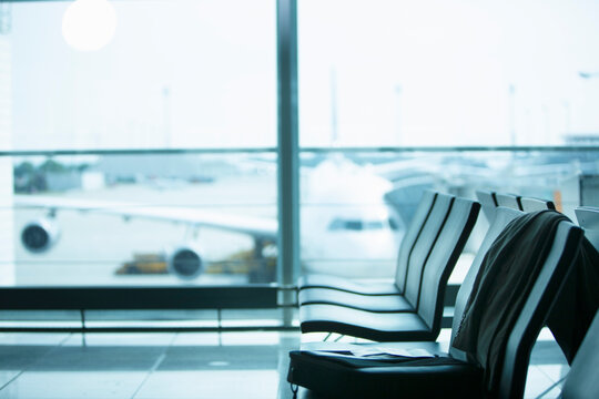 Row of seats at an airport with airplane in the background