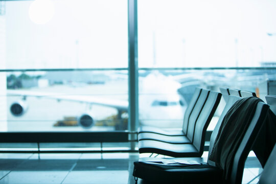Row of seats at an airport with airplane in the background
