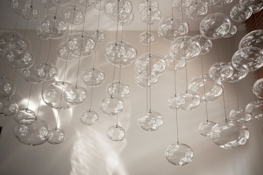 Glass orbs hung up on metal wire from the ceiling, organic forms.
