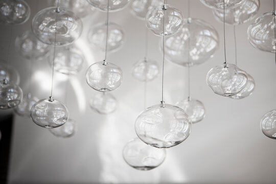 Glass orbs hung up on metal wire from the ceiling, organic forms.