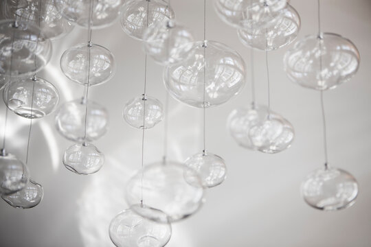 Glass orbs hung up on metal wire from the ceiling, organic forms.