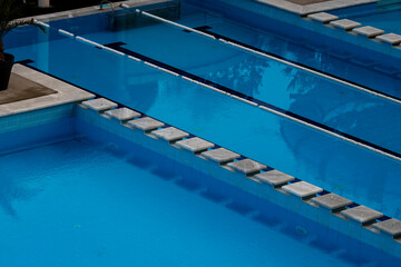 Clean swimming pool with clear blue water, bordered by white tiles