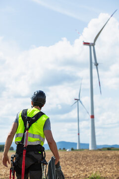 Wind farm technician working in the field near wind mills.