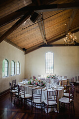 Elegant dining setup in a rustic venue for a special event with floral centerpieces and chandelier lighting