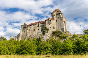 Obraz premium Ancient castles architecture in Europe. Austria medieval citadel made of bricks. Rocky walls of an old historical castle with towers and bridge on a sunny summer day, European landmark and history
