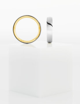 Wedding rings on top of white pedestal.