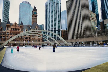 Fototapete Toronto Toronto residents enjoy skating on the ice rink at the Nathan Phillips square,with the Old City Town Hall during winter in Toronto,Ontario,Canada   © InnerPeace