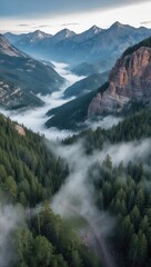 Mountains Forest Valley View. Morning Fog Clouds over Green Trees. Tall Cliff and Sharp Mountain Peaks in Background. Nature Landscape.