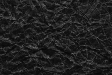 A sheet of old wrinkled black paper texture as background