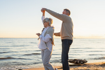 Keep moving. Romantic senior mature couple dancing together on beach outdoor recreation. Happy...