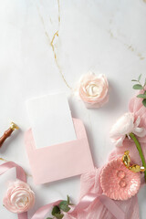 Flat lay composition with a pink envelope, blank card, and flowers on a marble background. Ideal for wedding invites, greeting cards, or romantic messages