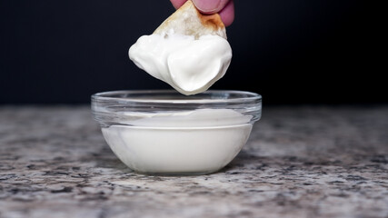 Dipping a crispy pierogie into creamy sour cream on a marble countertop for a delicious snack experience