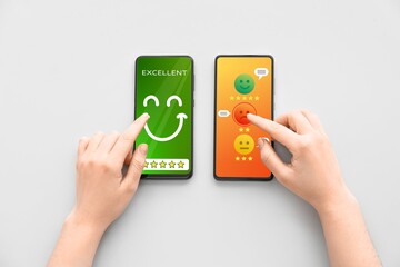 Hands of person with mobile phones responding to survey on grey background