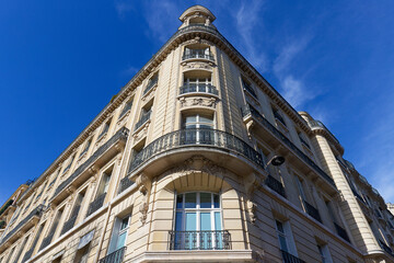 Fototapeta premium Exterior architecture of Traditional French house with typical balconies and windows in Paris. Traditional Parisian street light in the foreground.