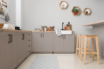 Interior of light kitchen with counters, utensils and stools