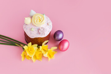 Traditional russian Easter ortodox cake with daffodil flower and colorful eggs on light pink background. Kulic, Kulich, Paska homemade bread with glaze. Spring christian holiday. Festive celebration
